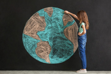 Little girl drawing planet on dark background. Earth Day celebration