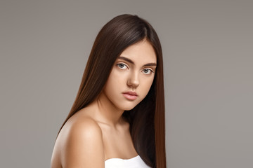 Young woman with beautiful straight hair on grey background