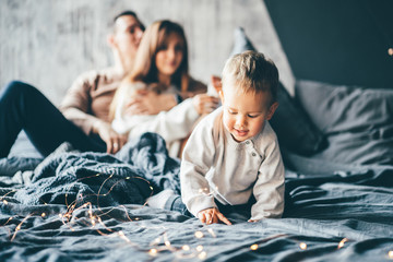 Family is having fun in bedroom. Parents with smile play like plane. Mother and father play with...