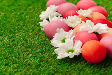 Colored Easter eggs on grass decorated with flowers