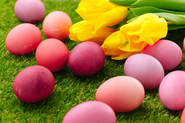 Fototapeta na wymiar Colored Easter eggs on grass decorated with flowers