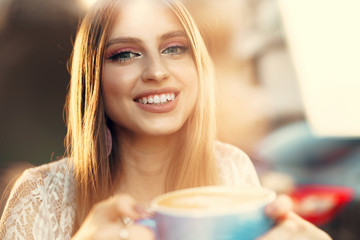 Portrait of a young woman having a cup of coffee and looking through the window