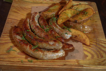 Rustic potatoes and fresh delicious fried chicken classic sausages. Close-up. Junk food.