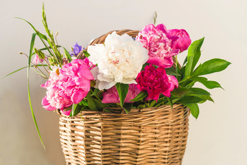 Obraz premium Beautiful bunch of pink, purple and white peonies in vintage wicker basket
