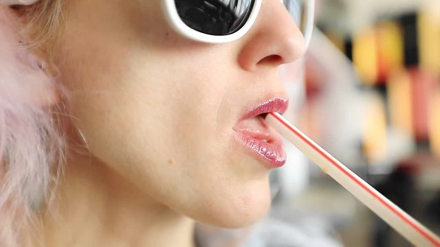 SLOW MOTION: Close up of young fashion caucasian woman drinking a cocktail in Hong Kong city, blurred skyline background.