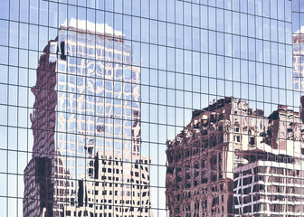 Fototapety  Stare budynki w Nowym Jorku odzwierciedlone w oknach nowoczesnego wieżowca, stonowanych kolorów tła miejskiego.