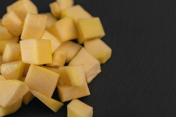 Pumpkin, zucchini pieces cut in cube slice on black background