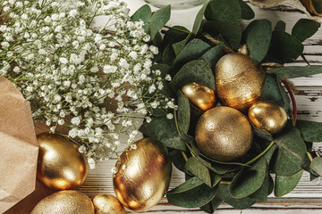 Golden colored eggs for Easter composition with floral branches
