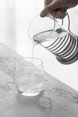 Clear cold water pouring into a glass with ice. Drinking water concept background