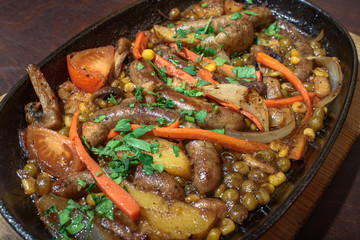 Hungarian frying pan (pork and beef sausages stewed with vegetables in dark beer) on a large wooden board. Tasty and healthy food. Close-up.