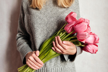 Happy woman holds tulips in her hands. Florist girl gathered a bouquet. Beautiful pink flowers....