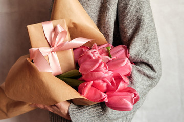 Happy woman holds tulips in her hands. Florist girl gathered a bouquet. Beautiful pink flowers. Blossom petal. Gift for the holiday celebration, springtime mood. Romantic surprise from a loved one