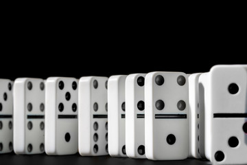 Dominoes standing in a row on black background