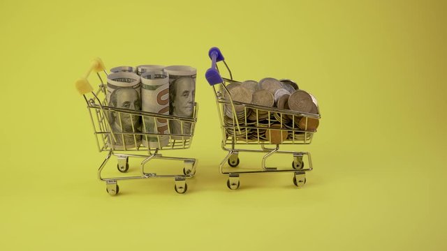 Animation. Shopping Carts carry coins, banknotes and credit cards. Yellow background. Finance and business concept. Close-up. 4K