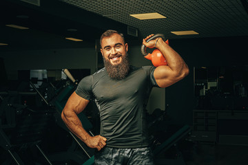 Bodybuilder doing exercises with dumbbells in a dark gym