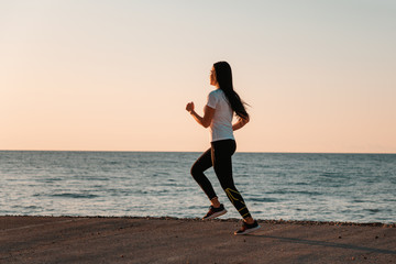 Fototapeta na wymiar The concept of sport and running. Woman in sportswear running on the track. In the background, the sea and the horizon line. Copy space. Sunset