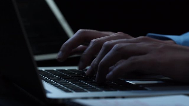 Close up hands of  businessman typing on laptop computer keyword at night while working overtime in office 