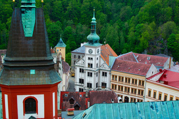 Obraz premium Red tower of the Church of St. Wenceslaus at the foreground with the Town Hall and Loket Market with typical colorful houses at the background (Czech Republic)