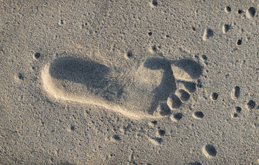 Close-up of footprint of child`s right foot in the sand.
