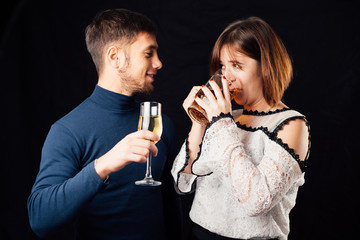 A man and a woman on a black background, a woman drinking beer and a man drinking champagne is a stereotypical activity