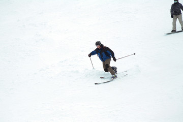 Fototapeta na wymiar A man goes skiing on a snow-covered ski track. Ski resort. A man on snowboard. Fast moving. Winter sport.