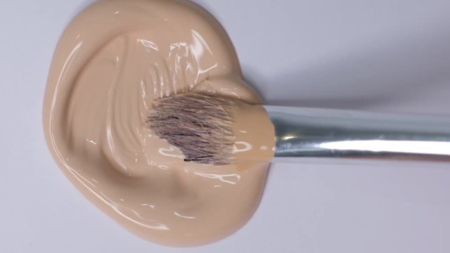 Smears of foundation for face. Cosmetic smear. Isolated on white background. Foundation face make-up smudge, smear. Cosmetic liquid foundation or bb cream beige. Closeup Slow motion.