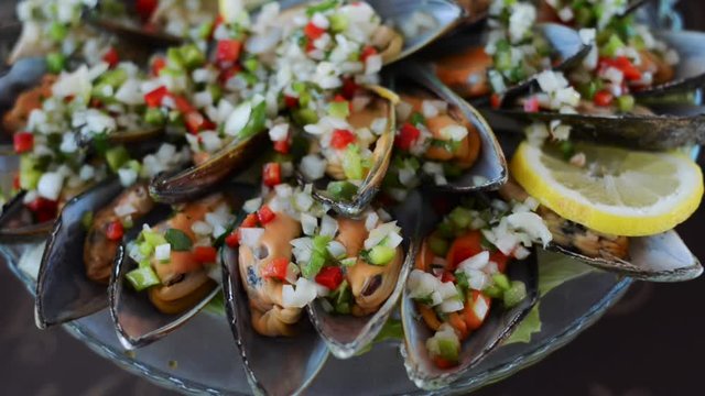 Motion shot, mussels dish with chopped vegetables and lemon on plate