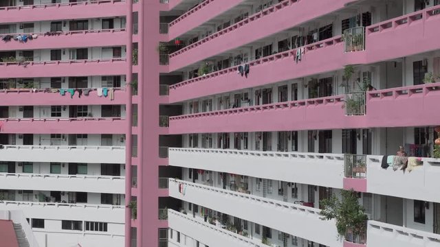 Panning view of a typical Singapore public housing building from the 1970s with modern architecture in the background on a quiet day.