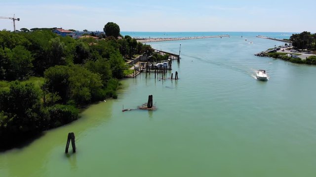 Porto Santa Margherita harbor with boat entering from the Adriatic sea, Caorle Italy, Aerial drone flyover shot