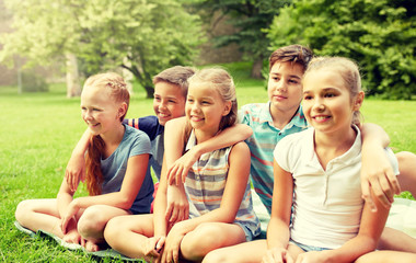 friendship, childhood, leisure and people concept - group of happy kids or friends sitting on grass in summer park