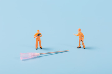 Syringe and miniature human and oral medicine and thermometer macro closeup on blue background