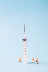 Syringe and miniature human and oral medicine and thermometer macro closeup on blue background