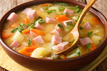 Slow cooked split pea soup with vegetables and ham close-up in a bowl. horizontal
