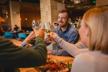 Group of young friends having fun in restaurant, talking and laughing while dining at table.
