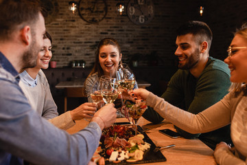 Group of young friends having fun in restaurant, talking and laughing while dining at table.