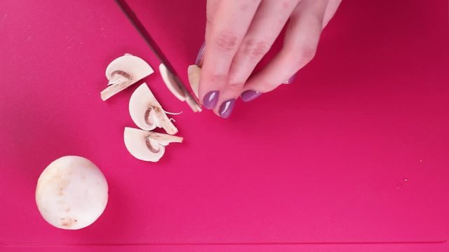 Cooking eat. Woman cuts the mushrooms on a pink board. Flat view