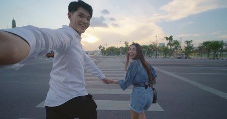 Sweet couple have romantic time while honeymoon trip in Bangkok city Thailand. POV of Young Asian couple holding hands and taking selfie while running and crossing the street in slow motion. - Powered by Adobe