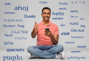 technology, communication and people concept - happy indian man with smartphone showing thumbs up...