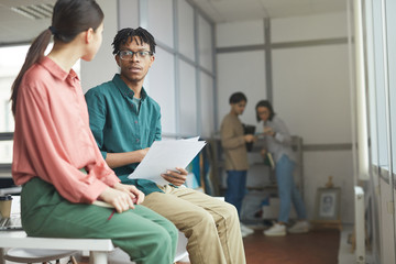 Obraz premium Two business colleagues sitting on the table and discussing report they preparing for the meeting together