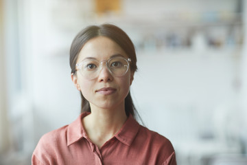 Portrait of serious young woman in eyeglasses looking at camera