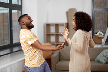 moving, repair and real estate concept - happy african american couple dancing at new home