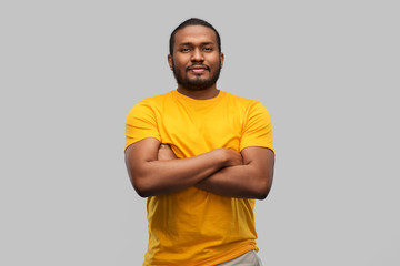 people concept - young african american man in yellow t-shirt with crossed arms over grey background