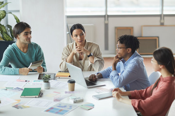 Group of young business people sitting at the table and discussing future plans in team during meeting