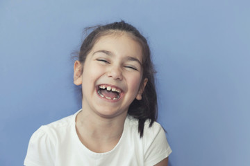 Portrait of happy laughing child girl on blue background. Smiling kid. Positive emotions.