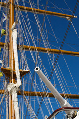 Obraz premium white gun on background masts of parsing ship mast sailing ship against the blue sky