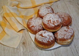 Donuts on plate on wooden table, kitchen cloths