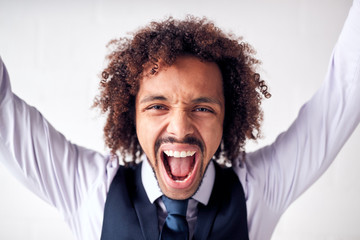 Portrait Of Happy Young Businessman Wearing Suit Celebrating Standing Against White Studio Wall