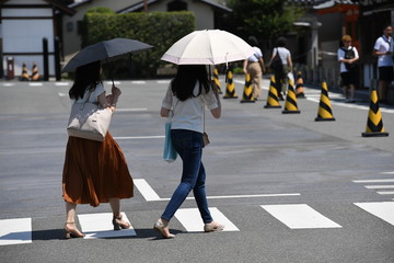 Two young japanese woman with umbrellas walking over a zebra crossing in Kyoto-Japan.