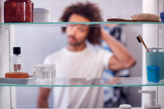 View Through Bathroom Cabinet Of Man Getting Ready For Work In The Morning