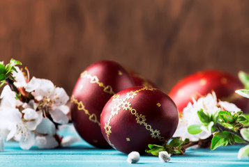Red Easter eggs. white flowers and willow branches on gentle Easter blue wood background